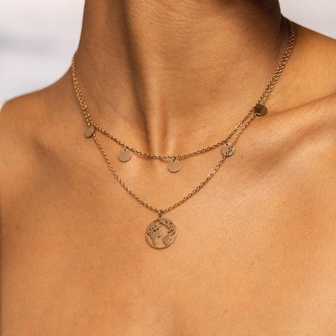 Goldene Kette mit Weltanhänger und Kreisen, getragen auf nackter Haut – PURELEI.
