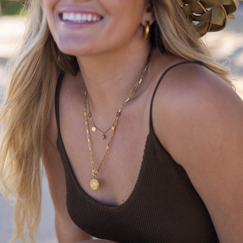 PURELEI Kalea Kette aus goldvergoldetem Edelstahl, filigran und elegant getragen im warmen Sonnenlicht am Strand