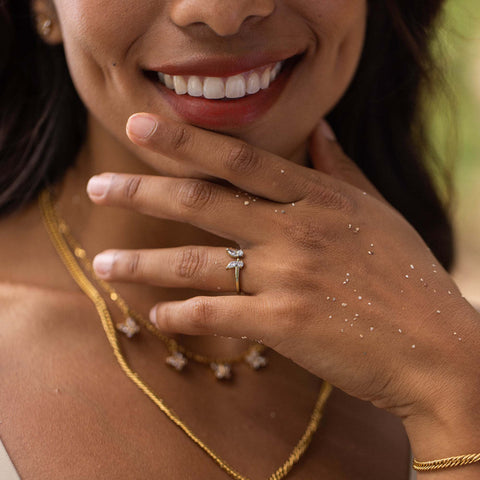 Zartes PURELEI Ringdesign mit funkelnden Details, getragen an einer Hand mit goldenen Ketten.